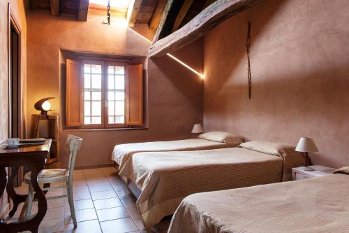 een slaapkamer met 2 bedden, een tafel en een raam bij Ostello Artemista Ass. Ostelli Lombardia in Spessa