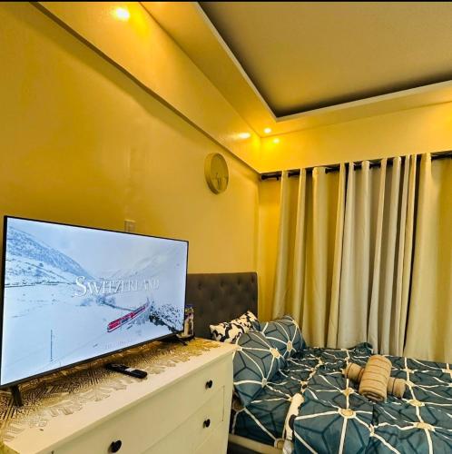 a bedroom with a large flat screen tv on a bed at Mariz Cozy and Elegant room in Manila