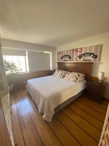 a bedroom with a white bed with a wooden floor at Gran Departamento Parque Arauco para 4 Personas in Santiago