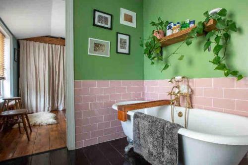 a bathroom with a pink and green wall and a bath tub at SEA BREEZE APARTMENT in Margate
