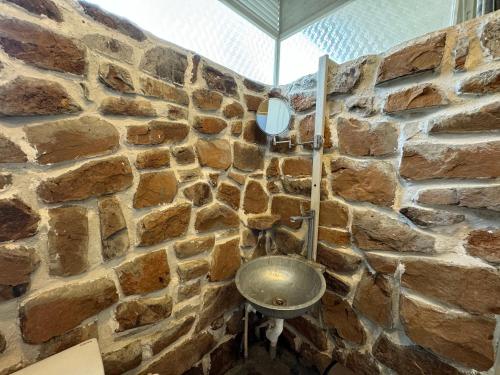 a stone bathroom with a metal toilet in a stone wall at Chikoo Farm inn in Bangalore