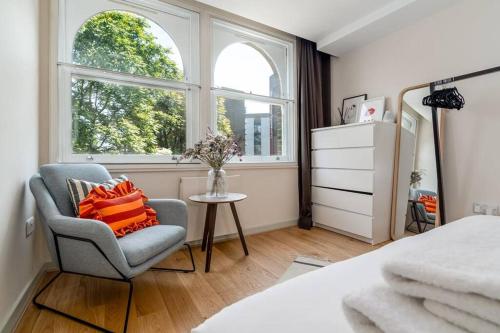 um quarto com uma cadeira, uma mesa e 2 janelas em 2 bedroom apartment in London Bridge em Londres