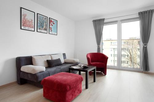 a living room with a couch and a red chair at Elite Apartments Nadmorski Brzeźno in Gdańsk