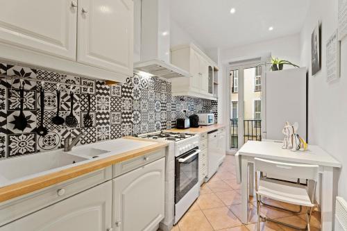 - une cuisine avec des placards blancs et un mur en carrelage noir et blanc dans l'établissement Nice - Renting - LASCARIS - Charm & Spacious & Comfort 3P Port Bonaparte, à Nice