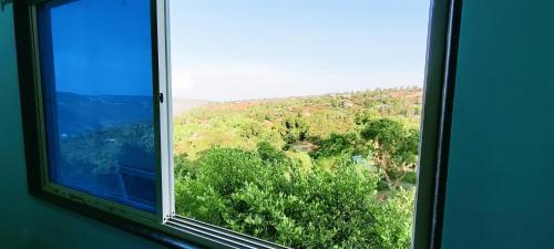 an open window with a view of a forest at Venus Villa in Panchgani