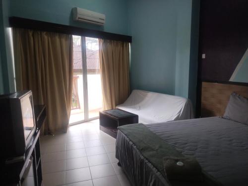 a bedroom with two beds and a tv and a window at JANAVIEW CONDOTEL 2 in Taiping