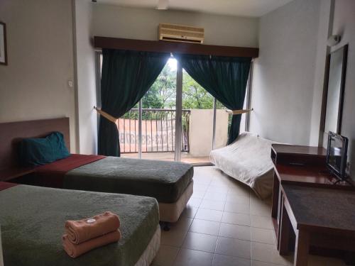 um quarto de hotel com três camas e uma varanda em JANAVIEW CONDOTEL 2 em Taiping