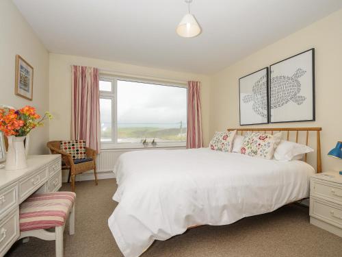 a bedroom with a large white bed and a window at Trevega in Polzeath