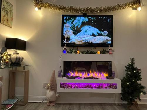 a living room with a fireplace with a tv above it at Hayloft at Bonnyside House in Bonnybridge