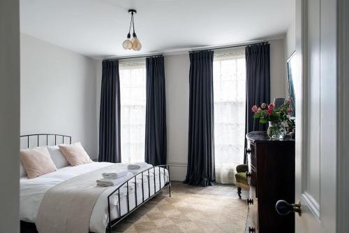 a bedroom with a bed and two windows at Trinity Square Georgian Townhouse in Margate