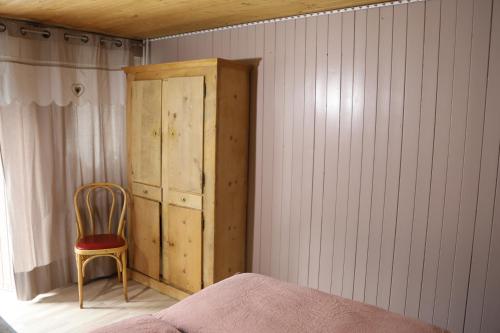 a bedroom with a wooden cabinet and a chair at MomenTine Appartement B&B in La Tine