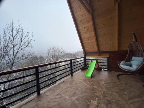 Un balcón de una cabaña con un tobogán verde en Villa Albani, en Peje