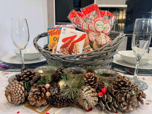 une table avec un panier de nourriture de Noël et des cônes de pin dans l'établissement Hayloft at Bonnyside House, à Bonnybridge