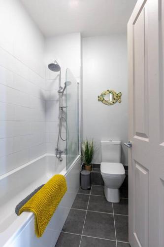a bathroom with a toilet and a shower with a yellow towel at Waves@Walpole - 2 Bed Flat with Amazing Sea Views in Margate