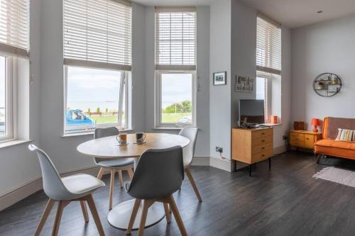 a living room with a table and chairs and windows at Waves@Walpole - 2 Bed Flat with Amazing Sea Views in Margate