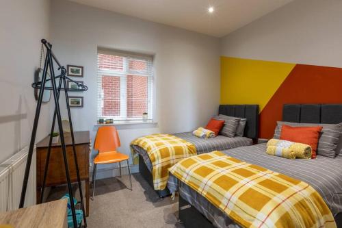 a bedroom with two beds and an orange chair at Waves@Walpole - 2 Bed Flat with Amazing Sea Views in Margate
