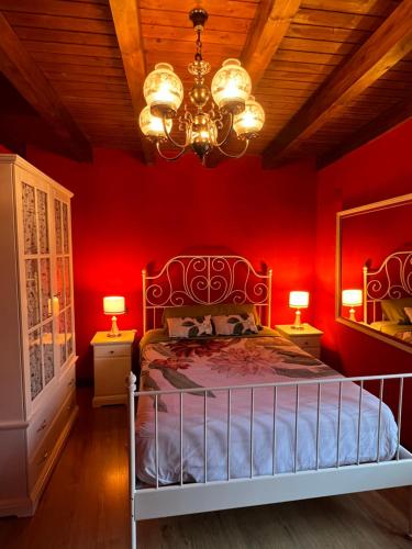 a bedroom with red walls and a bed with a chandelier at La Casa de Fefita (Stone house in a privileged environment 35 km from Bilbao) in Villanueva de Mena