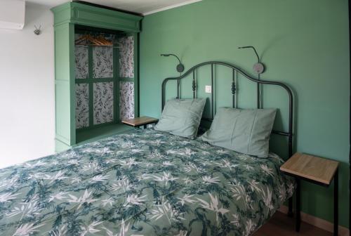 a bedroom with a bed with green walls at gite l'atelier du Trieu Robin in Beaumont