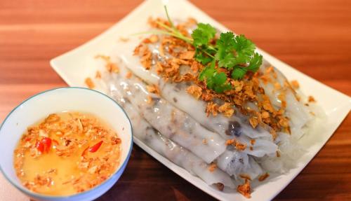 a plate of food and a bowl of soup on a table at Dom Hostel and Bar in Hoi An