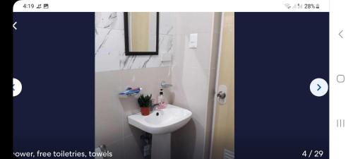 a bathroom with a white sink and a mirror at House of the rising sun in Ibajay