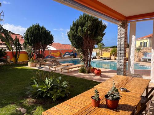 un patio trasero con una mesa de madera y una piscina en Ericeira Destination, en Ericeira