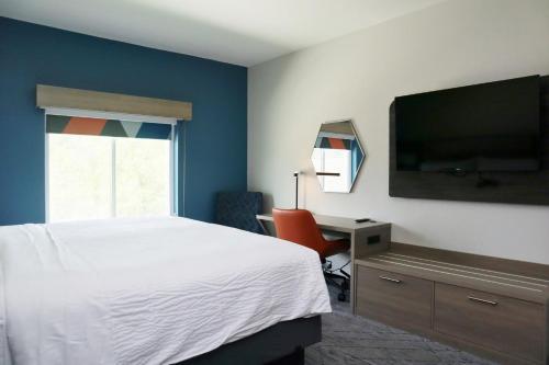 a bedroom with a bed and a desk and a television at Holiday Inn Express Baton Rouge North by IHG in Zachary
