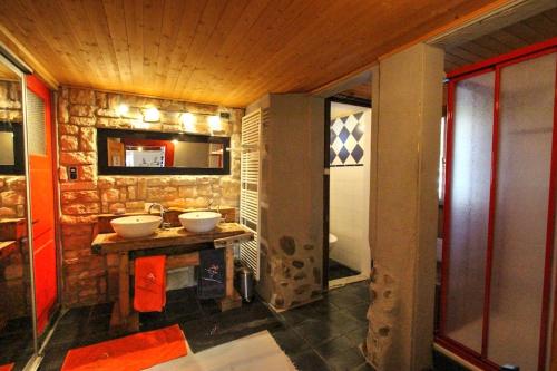 a bathroom with two sinks and a stone wall at MomenTine Appartement B&B in La Tine