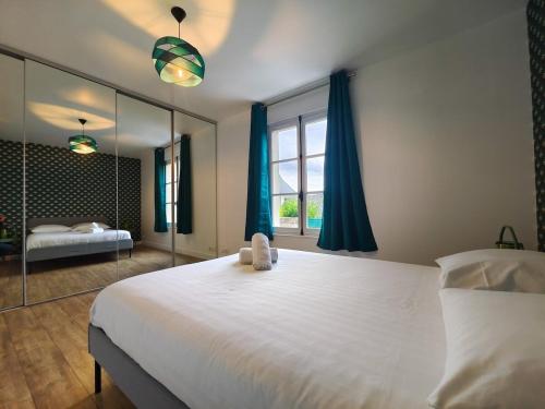 - une chambre avec un grand lit blanc et un miroir dans l'établissement Charmante petite maison en plein centre ville, à Caen