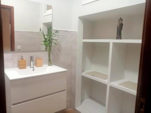 a white bathroom with a sink and shelves at Casa Colonial Vegueta in Las Palmas de Gran Canaria