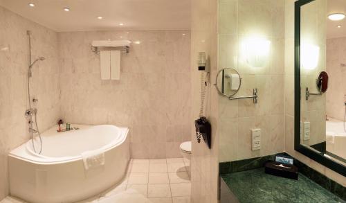 a bathroom with a tub and a toilet and a shower at Hilton Antwerp Old Town in Antwerp
