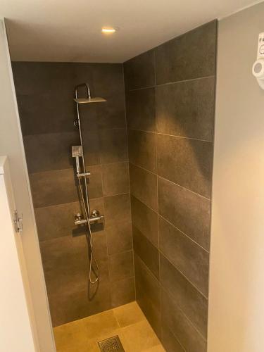 a bathroom with a shower with brown tile at Fin leilighet i Tromsø in Tromsø