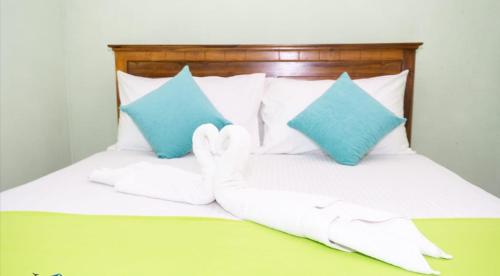 een bed met twee witte handschoenen en twee blauwe kussens bij Airport Villa D 87 in Katunayaka