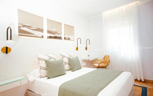 a white bedroom with a bed and a table at Hotel Oasis in Córdoba