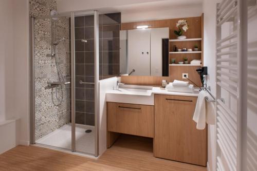 a bathroom with a shower and a sink and a mirror at DOMITYS L'ALLIACEE in Achères