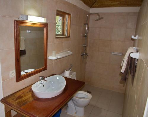 a bathroom with a sink and a toilet and a mirror at Auberge Plein Soleil in Mbodiène