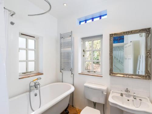 a white bathroom with a tub and a sink at The Courtyard in Pulborough