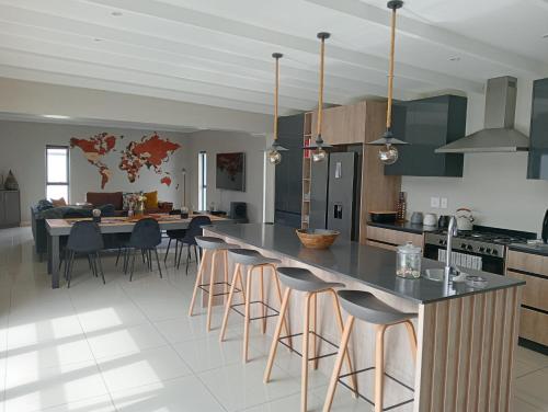 una cocina con una gran isla con taburetes de bar en Port Owen Holiday Home, en Velddrif