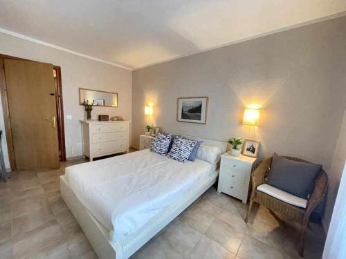 卡拉恩布拉內斯的住宿－Macarella Apatamento con piscina，卧室配有一张白色大床和一把椅子