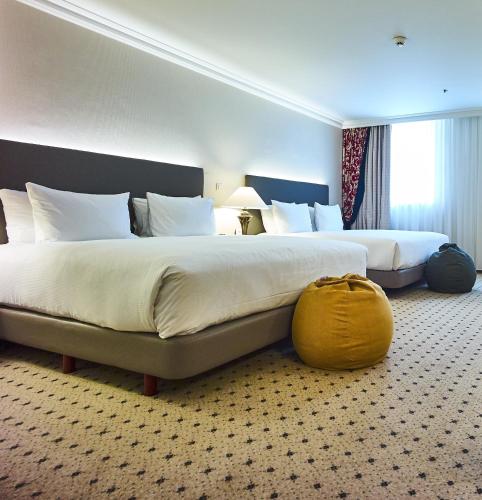 a hotel room with two beds and a yellow bag on the floor at Hilton Antwerp Old Town in Antwerp