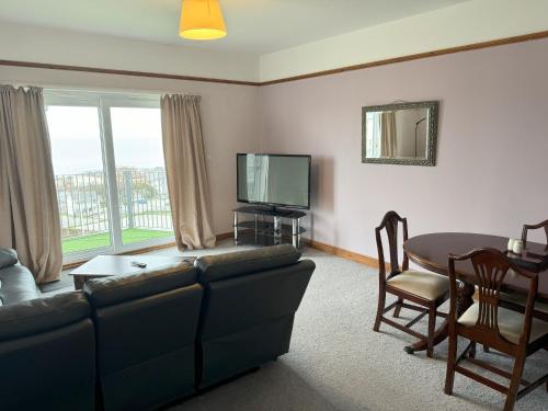 sala de estar con sofá, mesa y TV en Eton Court Apartments en Newquay