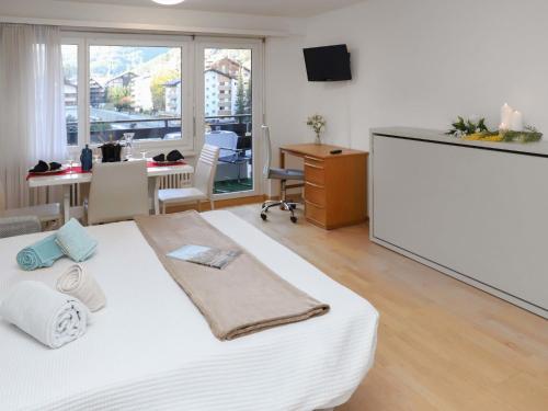 Schlafzimmer mit einem großen weißen Bett und einem Schreibtisch in der Unterkunft Apartment Residence A-3 by Interhome in Zermatt
