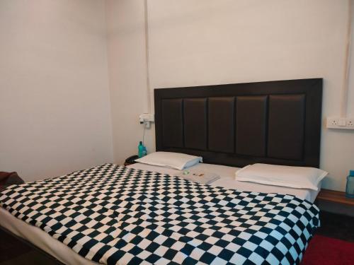 a bedroom with a bed with a black and white checkered bedspread at Kishan Home Stay in Mathura