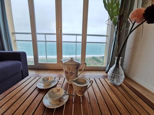 une table avec deux tasses de thé et un vase avec des fleurs dans l'établissement Apartment Val by Interhome, à Saint-Malo