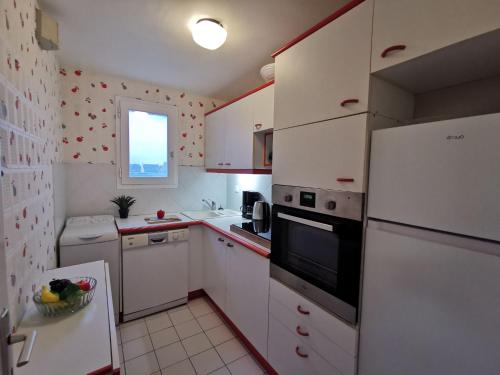 Elle comprend une petite cuisine avec des appareils électroménagers blancs et une fenêtre. dans l'établissement Apartment Val by Interhome, à Saint-Malo