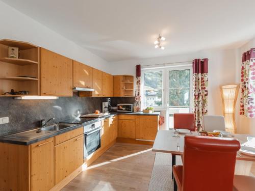 a kitchen with wooden cabinets and a table and a dining room at Apartment Stefanie Top 6 by Interhome in Bad Hofgastein