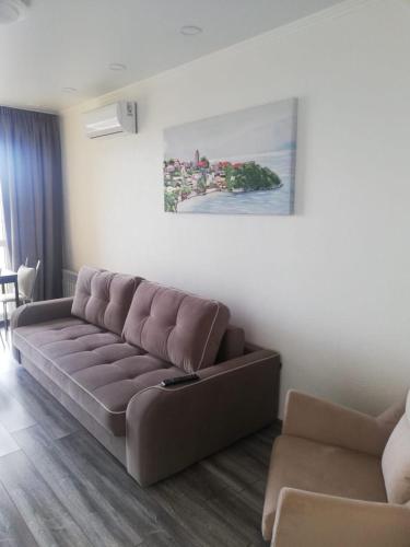 una sala de estar con un sofá marrón y una pintura en VIP apart 505 en Tsqnetʼi