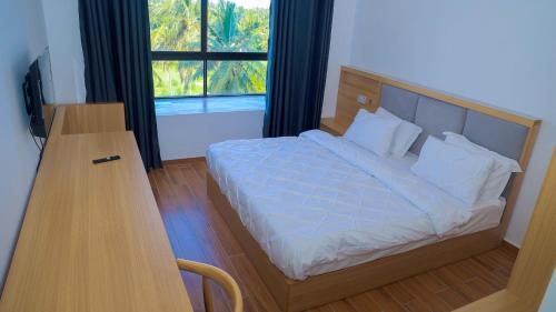um quarto com uma cama, uma secretária e uma janela em PALM VILLAGE BUSINESS HOTEL em Dar es Salaam