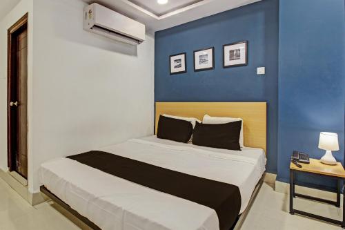 Schlafzimmer mit einem Bett mit blauer Wand in der Unterkunft Super OYO SilverKey 79803 Qualia Miyapur in Kondapur