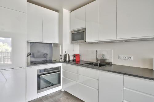 une cuisine blanche avec des armoires blanches et un évier dans l'établissement Chill & Work au pied de La Défense Arena, à Nanterre