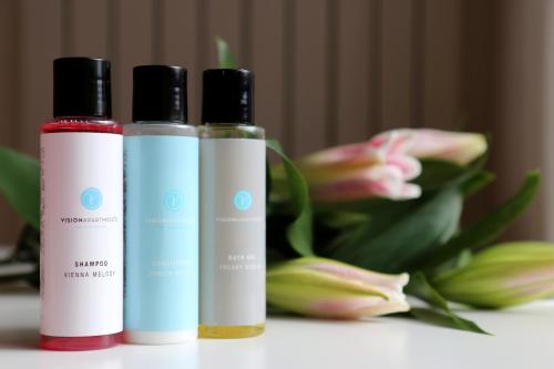 two bottles of liquids sitting on a table with flowers at VISIONAPARTMENTS St Sulpice - contactless check-in in Lausanne